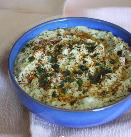 Baba Ganoush topped with parsley, paprika and olive oil in a blue bowl